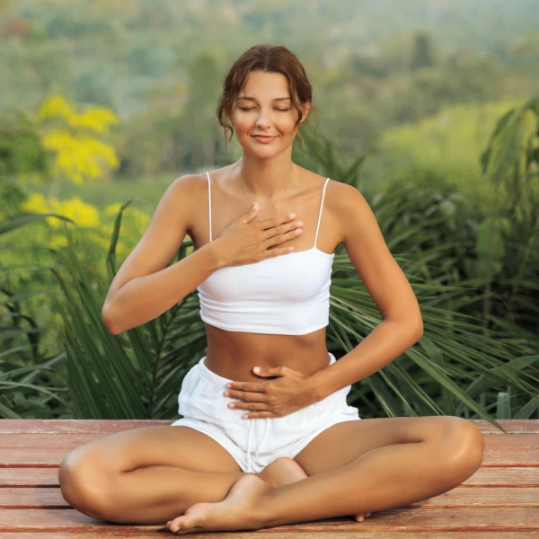 Femme en méditation, mains sur le cœur et le ventre, symbole de retour au calme et de régulation émotionnelle