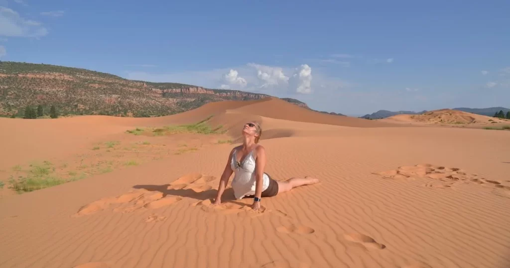 Démonstration de la posture du Cobra (Bhujangasana) réalisée dans un désert, illustrant l'ouverture du cœur et l'extension arrière en yoga.