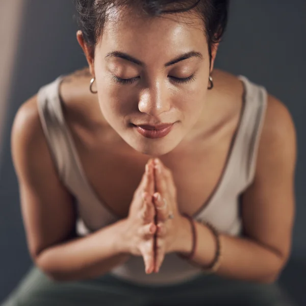 Femme en posture de méditation, les mains en prière.