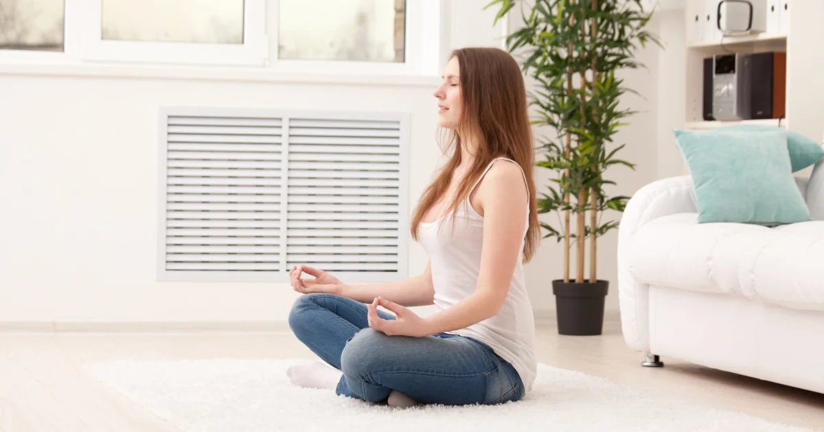 Femme méditant chez elle pour réduire le stress et apaiser l’esprit.