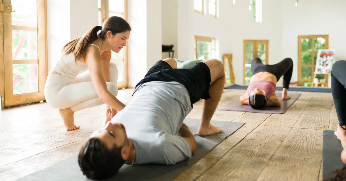 Instructrice guidant un élève pendant une séance de pédagogie du yoga.