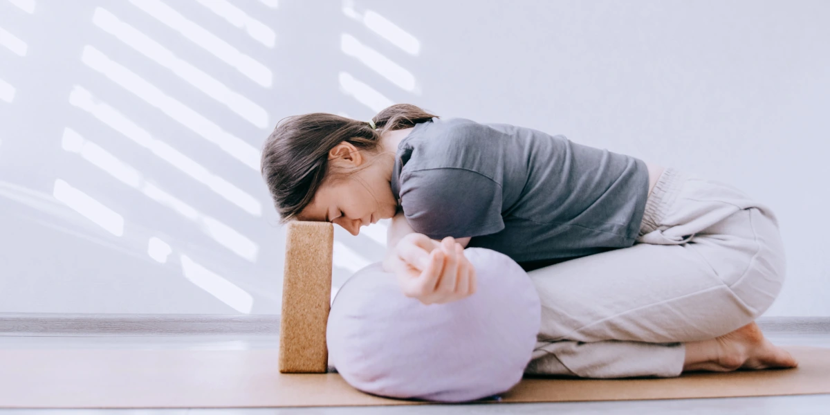 Femme assise dans une posture de relâchement avec des supports, illustrant la détente et la lenteur du Yin Yoga.